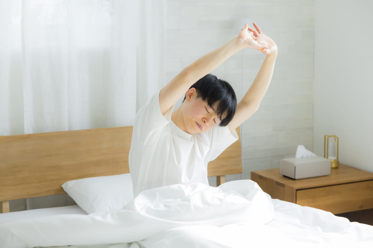 寝室で伸びをする男性